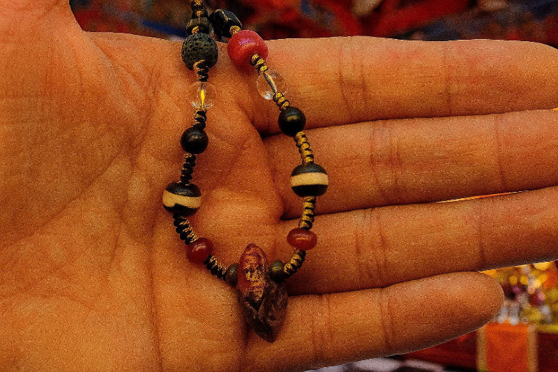 Close up of sacred one-eye Dzi agate and handcrafted black and yellow braided cord.
