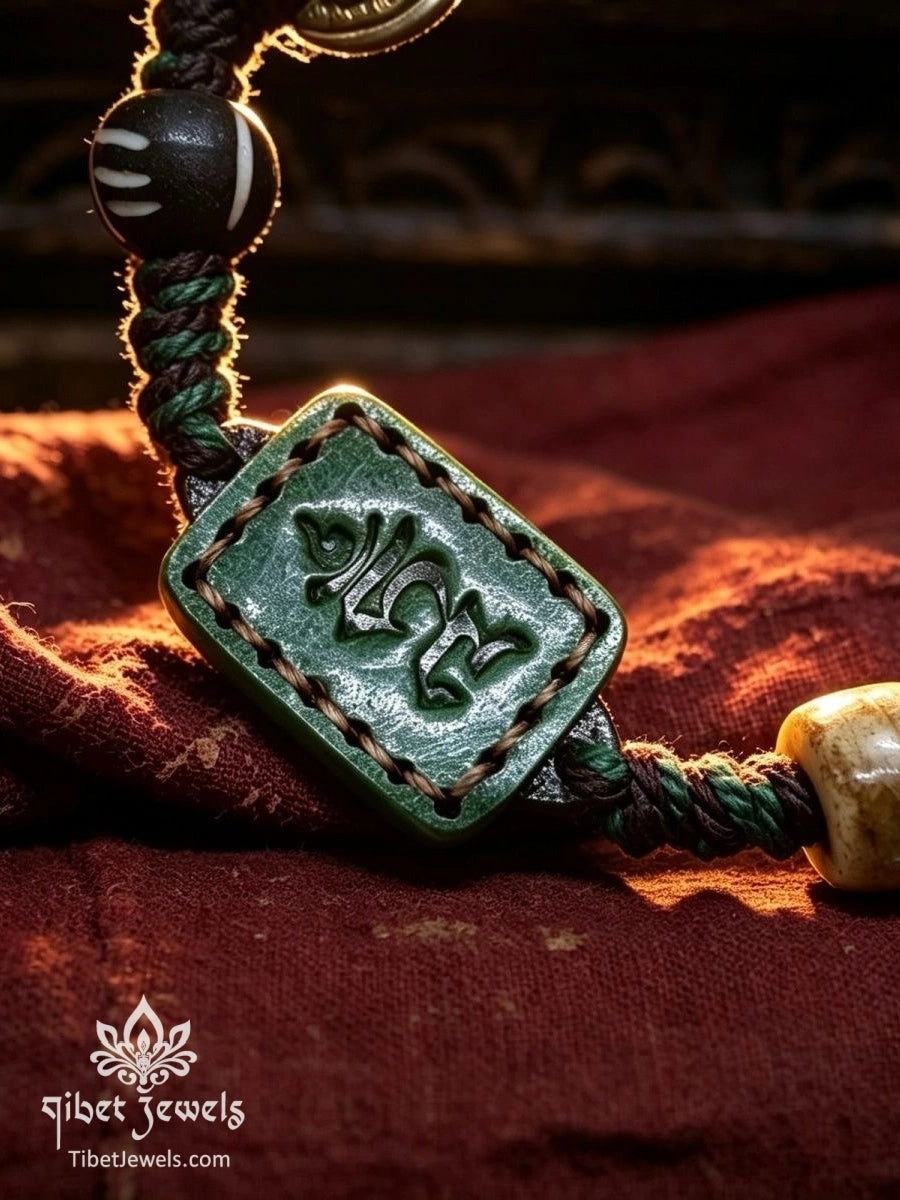 Back of green leather amulet embossed with a Tibetan syllable, beside yak bone beads on braided cord