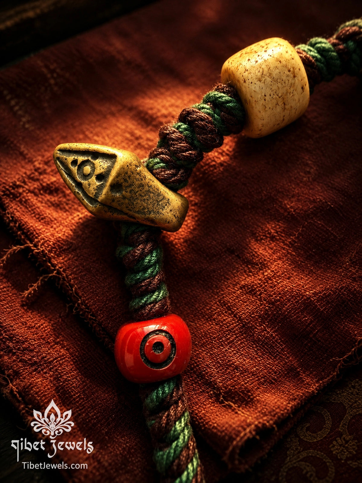 Copper Nyagla Chacha, red agate bead and yak bone barrel bead on a hand-braided cord bracelet