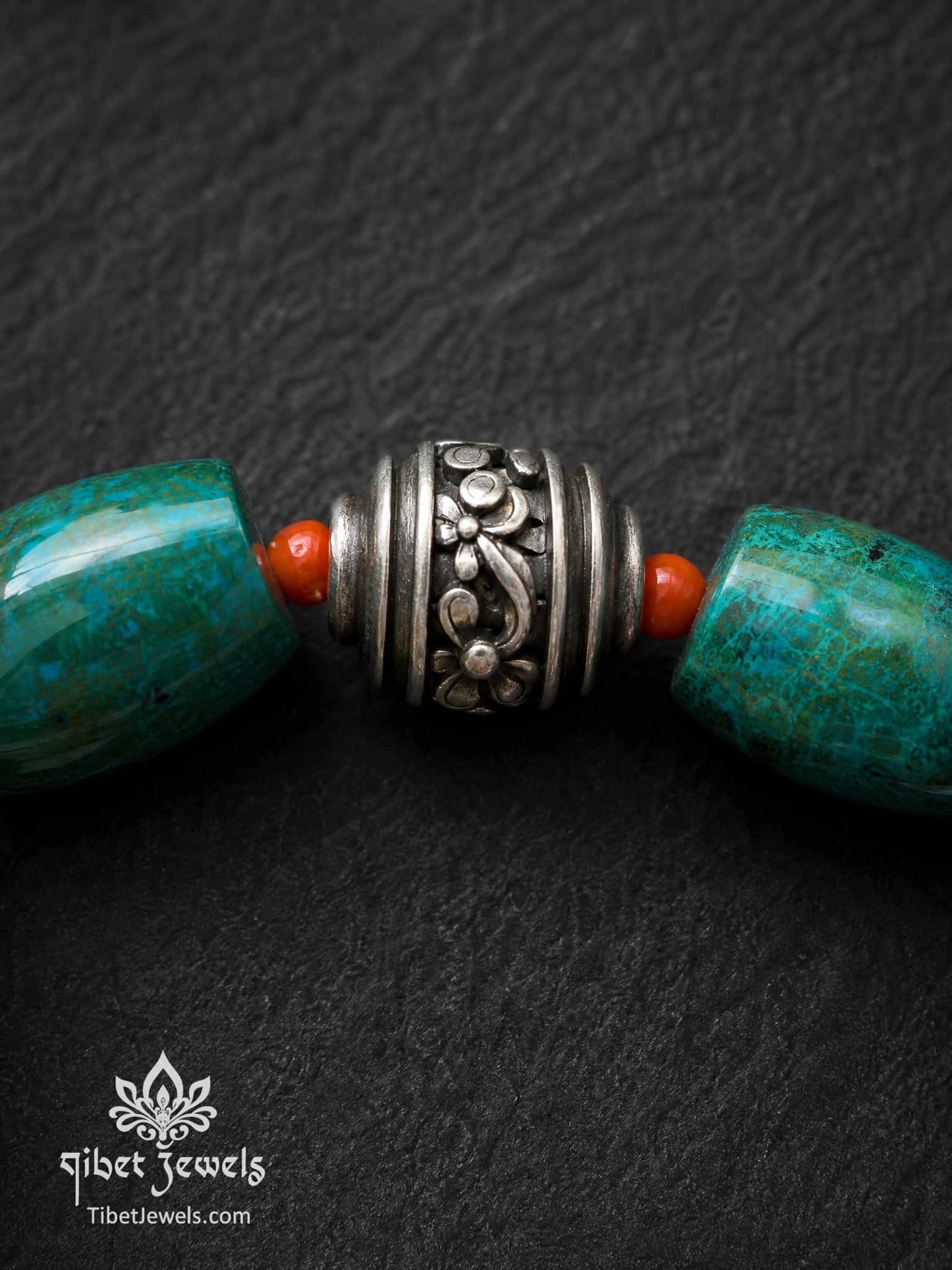 Close-up of engraved old Tibetan silver focal bead with copper accents on Phoenix Stone bracelet.