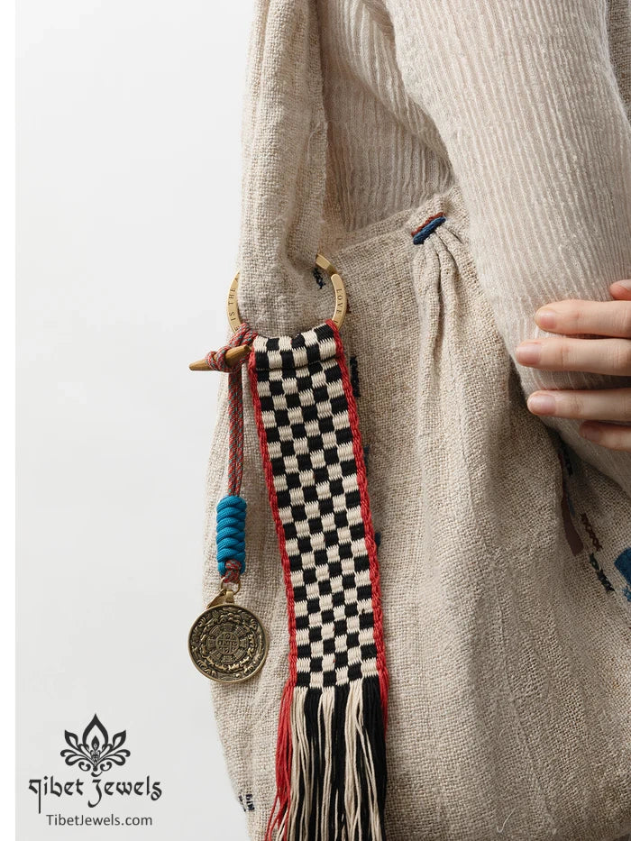 Tibetan bagua brass charm clipped to a leather backpack as a protective amulet.
