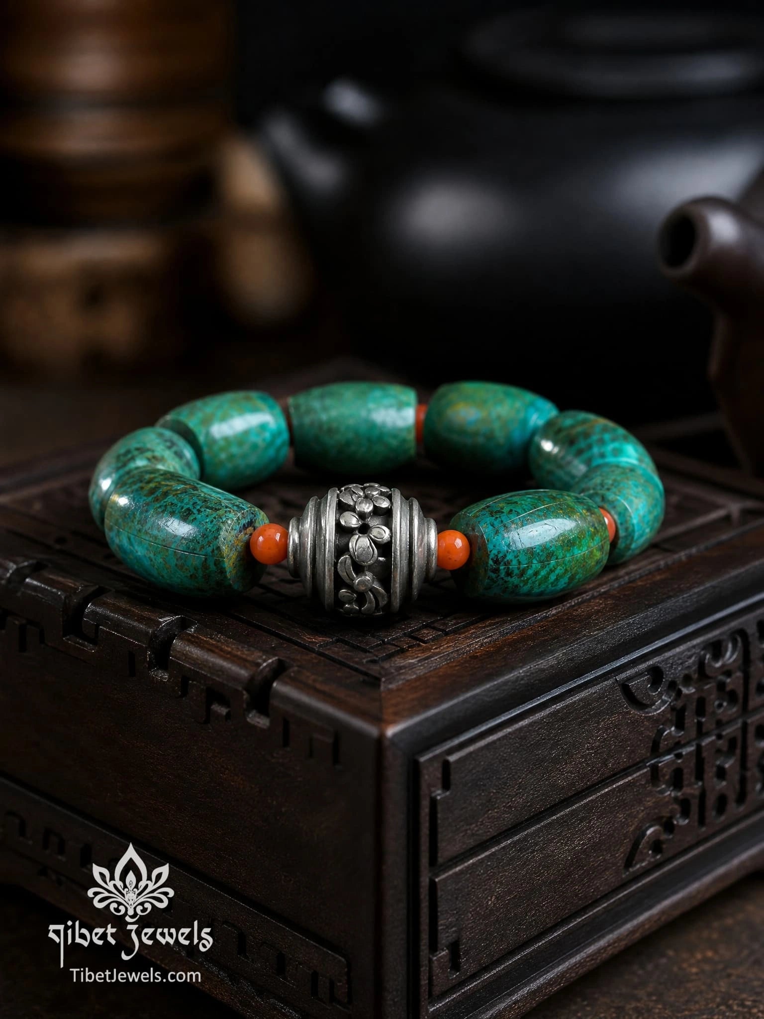 Phoenix Stone bracelet displayed on a dark wood stand with red agate spacers and Tibetan silver bead.