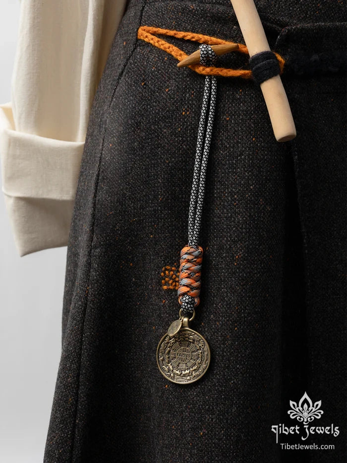Tibetan bagua brass charm clipped to a leather backpack as a protective amulet.