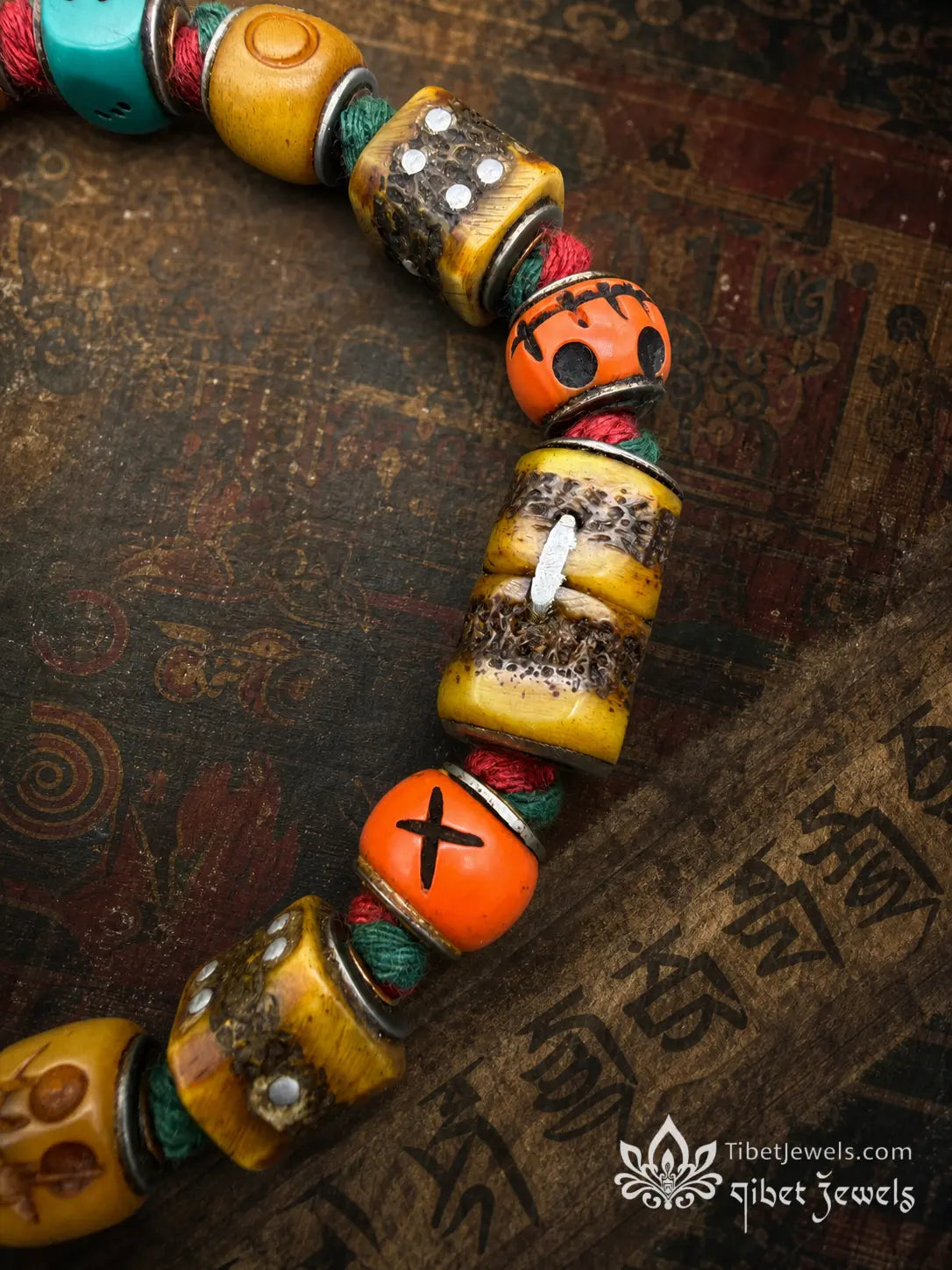 Antique Lima brass prosperity bell on a handwoven red-and-green cord dice bracelet.