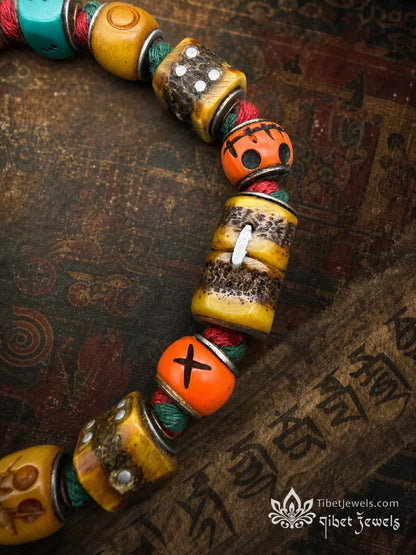 Antique Lima brass prosperity bell on a handwoven red-and-green cord dice bracelet.