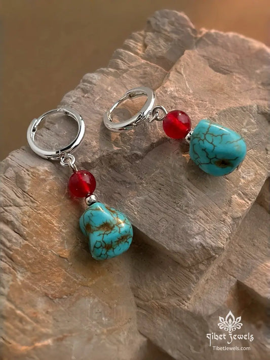 Tibetan Sky & Ember drop earrings with natural turquoise nugget and red agate bead on silver-plated hoops.