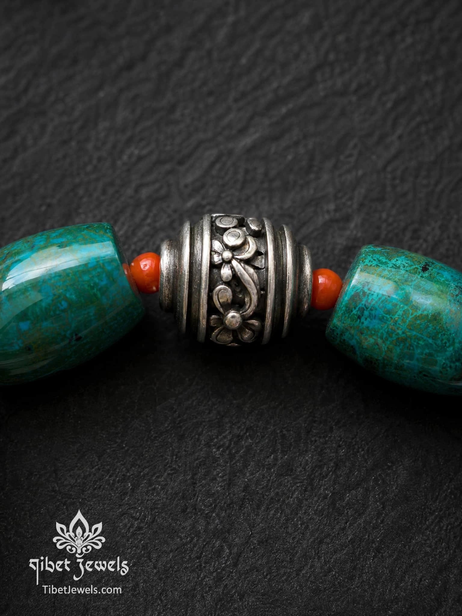 Close-up of engraved old Tibetan silver focal bead with copper accents on Phoenix Stone bracelet.