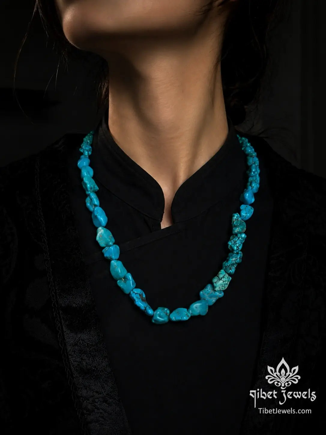 Raw Tibetan turquoise nugget necklace displayed on grey fabric, showing full 25-inch length and natural stone variation.